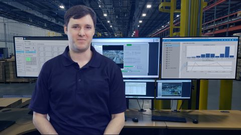 Austin Santich in front of a software command center in a distriubution center.