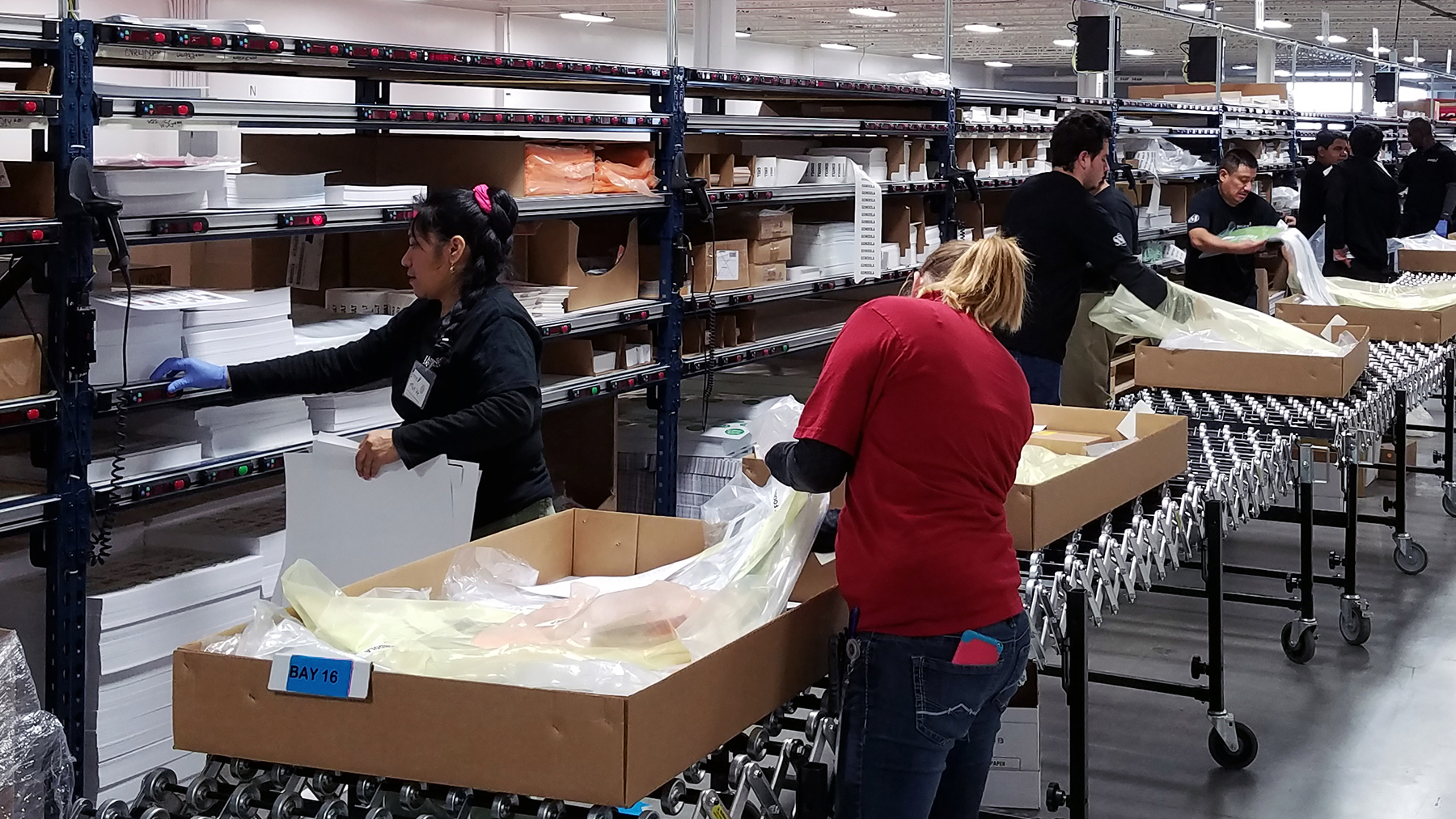 Line of order pickers in a fulfillment center using Lightning Pick pick-to-light system to select orders.
