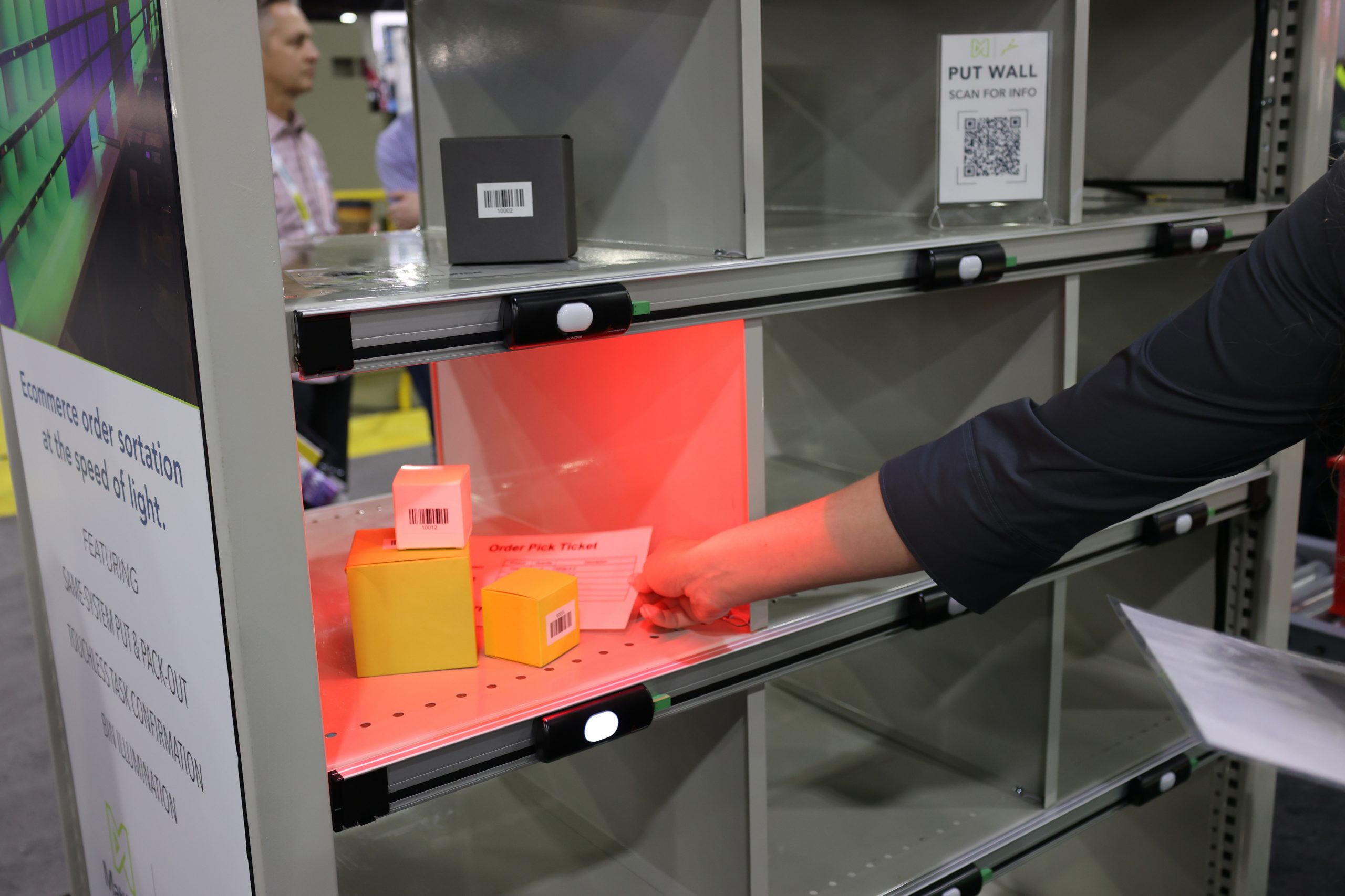 Operator performing put-to-light demo with bin illumination in a trade show booth
